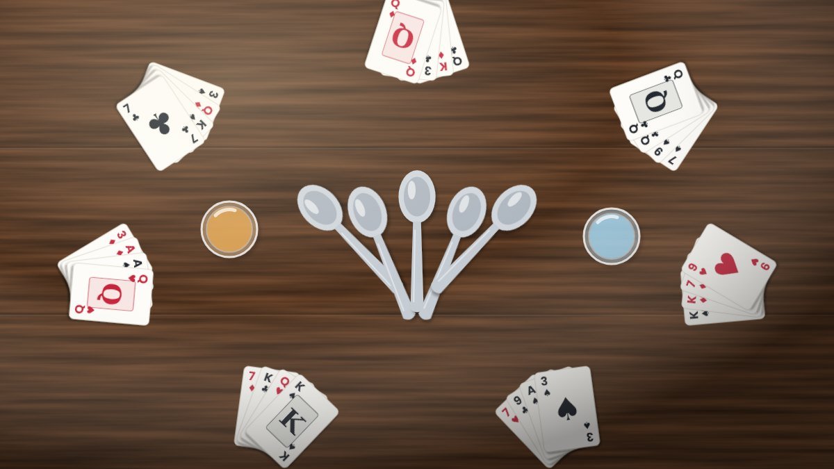 Large group of friends laughing while playing a card game around a crowded dining table